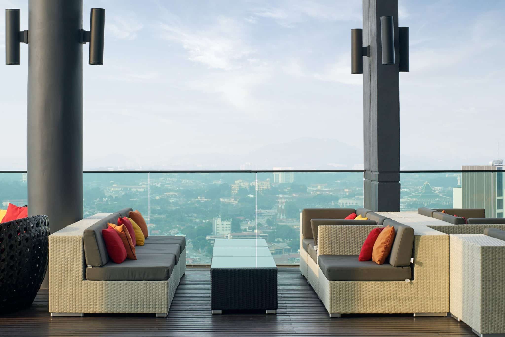 Modern rooftop poolside lounge area with city view and contemporary furniture.